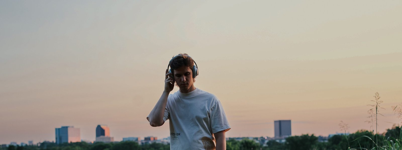 Photo of JBarr standing in a field with a city skyline behind him as the sun is setting